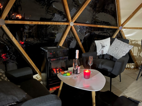 Cozy interior of Dôme Lodge at Campsite Moulin de Chaules, featuring modern chairs and an electric stove.
