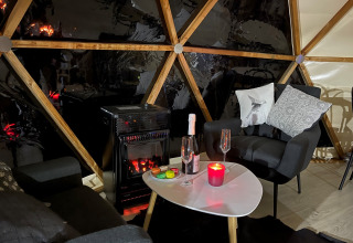 Cozy interior of Dôme Lodge at Campsite Moulin de Chaules, featuring modern chairs and an electric stove.