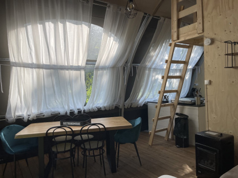 Interieur van Lodge ‘Big Oak XXL’ op Moulin de Chaules met eettafel, ladder en kleine keuken.