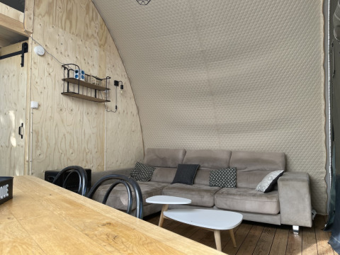 Interno di una tenda safari Lodge Big Oak XXL al Camping Moulin de Chaules con divano e pareti in legno.