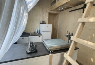 Interieur van safari tent Lodge 'Big Oak XXL' op Moulin de Chaules, Frankrijk, met een slaapzolder en keukenblok.