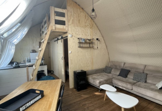 Interieur van safaritent Lodge Big Oak XXL op camping Moulin de Chaules in Frankrijk met bank en loft.