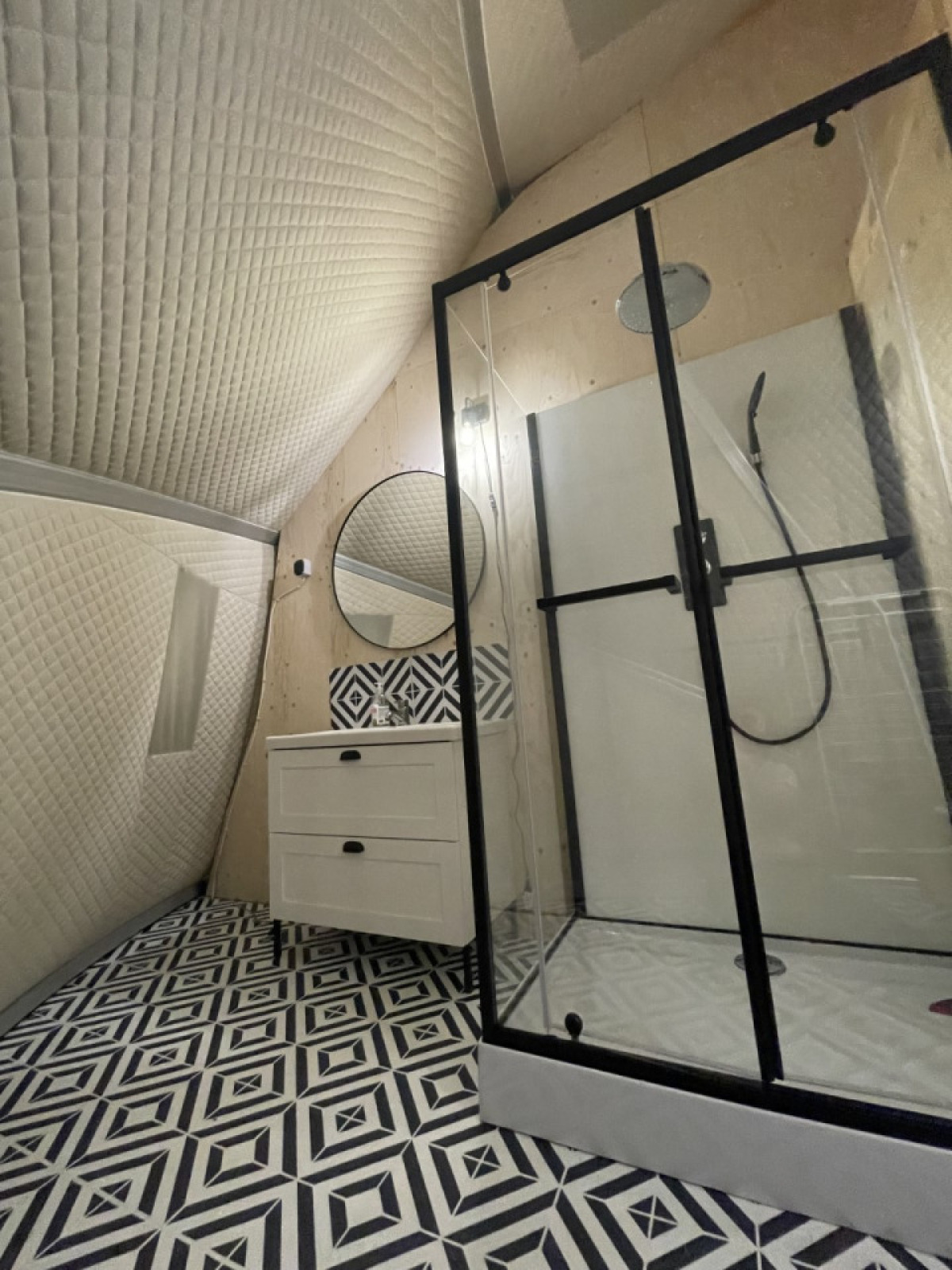 Moderne badkamer in een safaritent met zwart-wit geometrische vloer en glazen douche op een Franse camping.