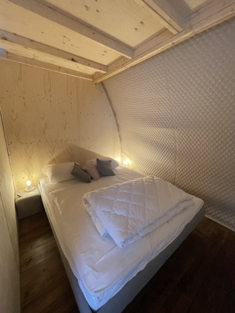 Cozy bedroom inside the Lodge Big Oak XXL safari tent at Campsite Moulin de Chaules, with wooden walls.