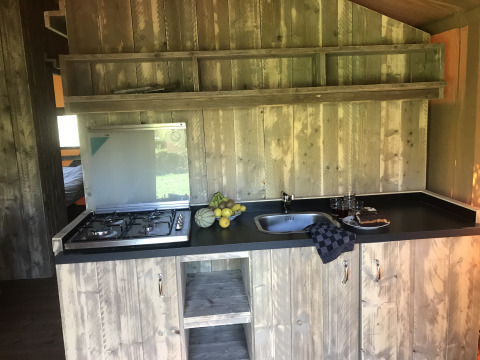 Rustieke houten keuken met gasfornuis en spoelbak in Woody Safari Tent + jacuzzi bij Flower Camping de la Trye, Frankrijk.