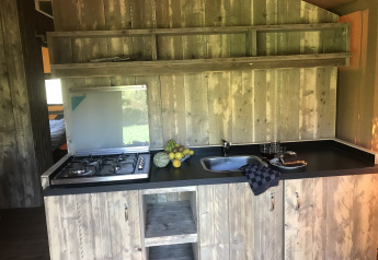 Rustieke houten keuken met gasfornuis en spoelbak in Woody Safari Tent + jacuzzi bij Flower Camping de la Trye, Frankrijk.