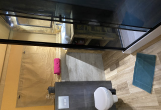 Binnenbadkamer van Woody Safari Tent met modern toilet, wastafel en kleurrijk opgerolde handdoeken.
