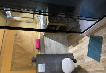 Binnenbadkamer van Woody Safari Tent met modern toilet, wastafel en kleurrijk opgerolde handdoeken.