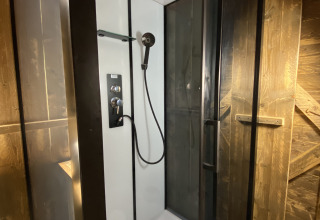 Moderne douche met glazen deuren en regendouche in Woody Safari Tent met jacuzzi bij Flower Camping de la Trye.