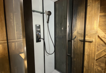 Moderne douche met glazen deuren en regendouche in Woody Safari Tent met jacuzzi bij Flower Camping de la Trye.
