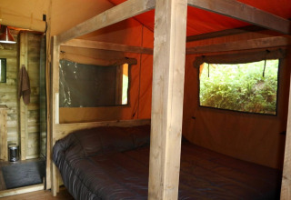 Interior view of the Safari Lodge XL tent at Campsite Moulin de Chaules in France, showing a double bed.