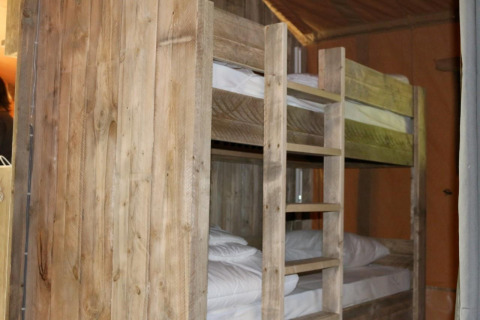Wooden bunk beds inside a Safari Lodge XL tent at Campsite Moulin de Chaules in France.