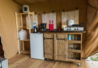 Interieur van een safaritent in Centro Vacanze San Marino met keukenblok, gasfornuis, koelkast en glazen.