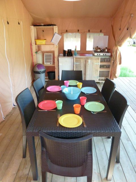 Essbereich im Safarizelt im Centro Vacanze San Marino mit buntem Geschirr und moderner Campingausstattung.