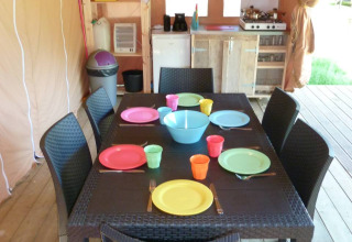 Comedor en una tienda safari de Centro Vacanze San Marino, dispuesto con platos y vasos de colores vibrantes.