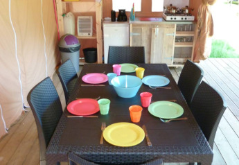 Zona pranzo in una tenda safari al Centro Vacanze San Marino, apparecchiata con piatti colorati.