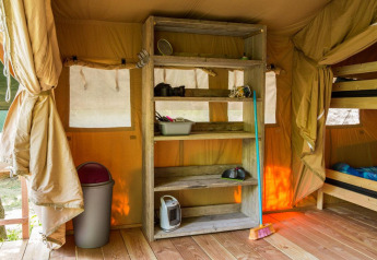 Binnenkant van een safaritent bij Centro Vacanze San Marino met houten rek, stapelbed en schoonmaakspullen.