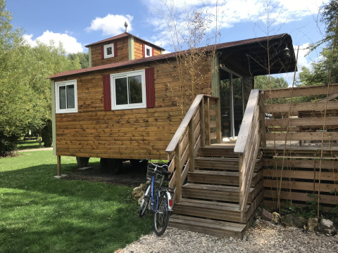 Tiny house Château Mobile van hout met trap en fiets, gelegen bij Flower Camping de la Trye in Frankrijk.