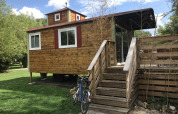 Tiny house Château Mobile van hout met trap en fiets, gelegen bij Flower Camping de la Trye in Frankrijk.