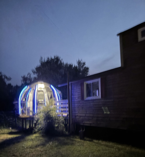 Château Mobile en verlichte jacuzzi bij Flower Camping de la Trye in Frankrijk, gefotografeerd in de schemer.