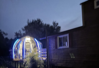 Château Mobile en verlichte jacuzzi bij Flower Camping de la Trye in Frankrijk, gefotografeerd in de schemer.