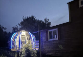 Château Mobile et jacuzzi éclairé au Flower Camping de la Trye, France, pris au crépuscule.