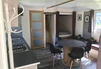 Vue intérieure du Château Mobile + jacuzzi au Flower Camping de la Trye, avec cuisine et coin repas.