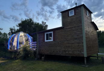 Tiny house en bois avec jacuzzi dôme illuminé, Flower Camping de la Trye en France, au crépuscule.