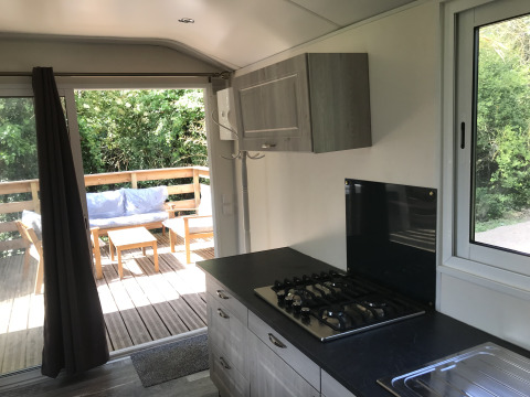 Moderne tiny house keuken met gaskookplaat, terras en zitje buiten bij Flower Camping de la Trye.