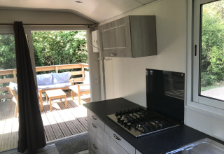 Moderne tiny house keuken met gaskookplaat, terras en zitje buiten bij Flower Camping de la Trye.