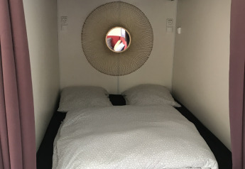 Alcôve intime avec lit double, décoration murale circulaire et miroir dans un tiny house à Flower Camping de la Trye.