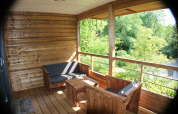 Veranda in legno con posti a sedere e vista sulla foresta allo chalet al Campsite Moulin de Chaules, Francia.