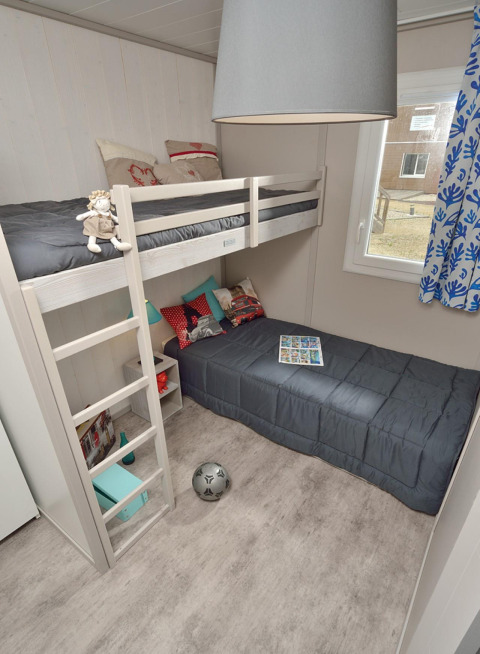 Gemütliches Schlafzimmer mit Etagenbett und Fenster im Wooden Chalet auf dem Campingplatz Moulin de Chaules.