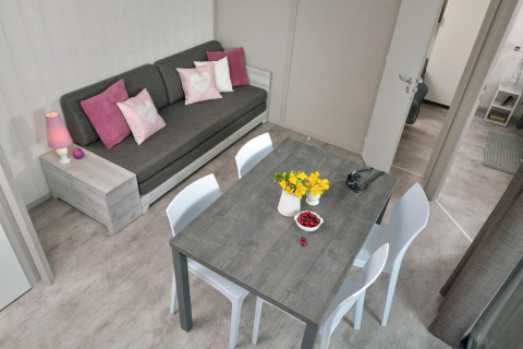 Moderne stue på en træhytte ved Campsite Moulin de Chaules med sofa, spisebord og blomsterdekoration.