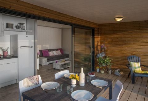 Chalet en bois au Camping Moulin de Chaules en France, avec terrasse aménagée et salon intérieur convivial.