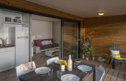 Holzchalet mit moderner Terrasse, Esstisch und Wohnzimmer bei Campsite Moulin de Chaules in Frankreich.