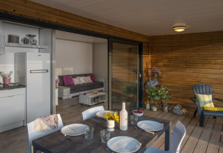 Chalet en bois au Camping Moulin de Chaules en France, avec terrasse aménagée et salon intérieur convivial.