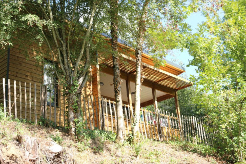 Chalet in legno presso il campeggio Moulin de Chaules in Francia, immerso tra alberi e natura verde.