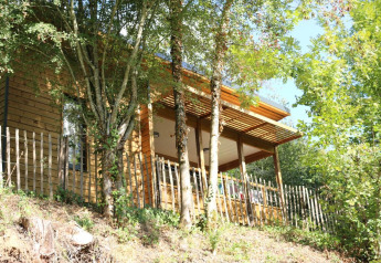 Wooden chalet at Campsite Moulin de Chaules in France, nestled among trees and surrounded by nature.