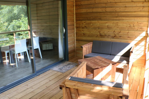 Holzveranda mit bequemen Sitzmöbeln, am Wooden chalet im Campingplatz Moulin de Chaules in Frankreich.
