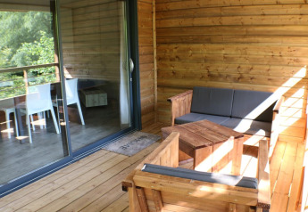 Træterrasse med behagelige møbler og udsigt, ved Wooden chalet på Camping Moulin de Chaules i Frankrig.