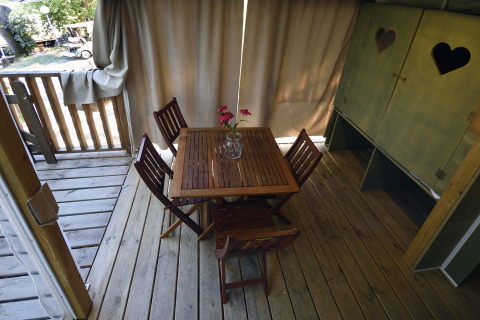 Houten veranda met tafel en vier stoelen in het Air Lodge safaritent bij Centro Vacanze San Marino.