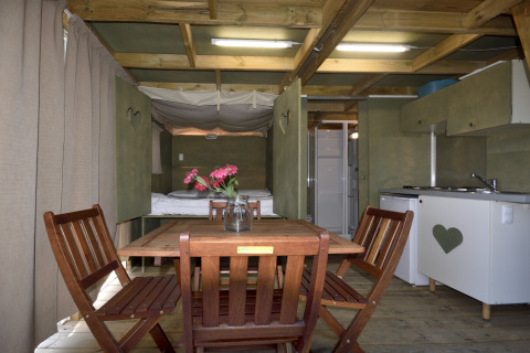 Vista interna della tenda safari Air Lodge al Centro Vacanze San Marino con mobili in legno e angolo cottura.