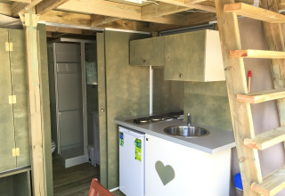 Indvendig visning af Air Lodge safari telt med lille køkken, bad, trappe og træindretning.