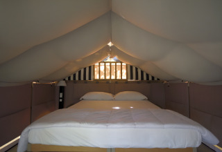 Dobbeltseng i «Air Lodge»-safari-teltet på Centro Vacanze San Marino, med polstrede vægge og loft.