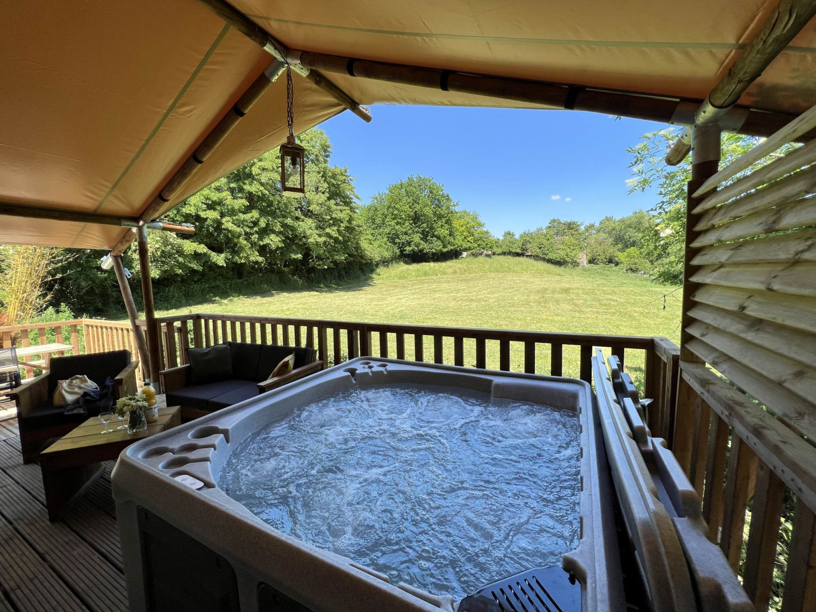 Safari Tent XXL met buitenjacuzzi bij Flower Camping de la Trye in Frankrijk, uitkijkend op een veld.