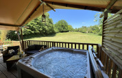 Safari Tent XXL met buitenjacuzzi bij Flower Camping de la Trye in Frankrijk, uitkijkend op een veld.