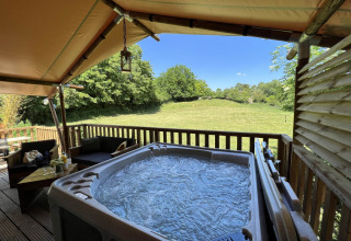 Safari Tent XXL met buitenjacuzzi bij Flower Camping de la Trye in Frankrijk, uitkijkend op een veld.