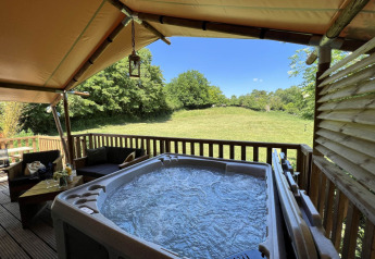 Safari Tent XXL with outdoor jacuzzi at Flower Camping de la Trye in France, overlooking a green field.