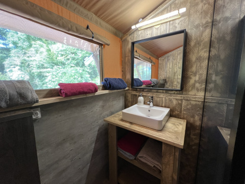Badkamer in Safari Tent XXL met wastafel, spiegel en handdoeken bij Flower Camping de la Trye, Frankrijk.